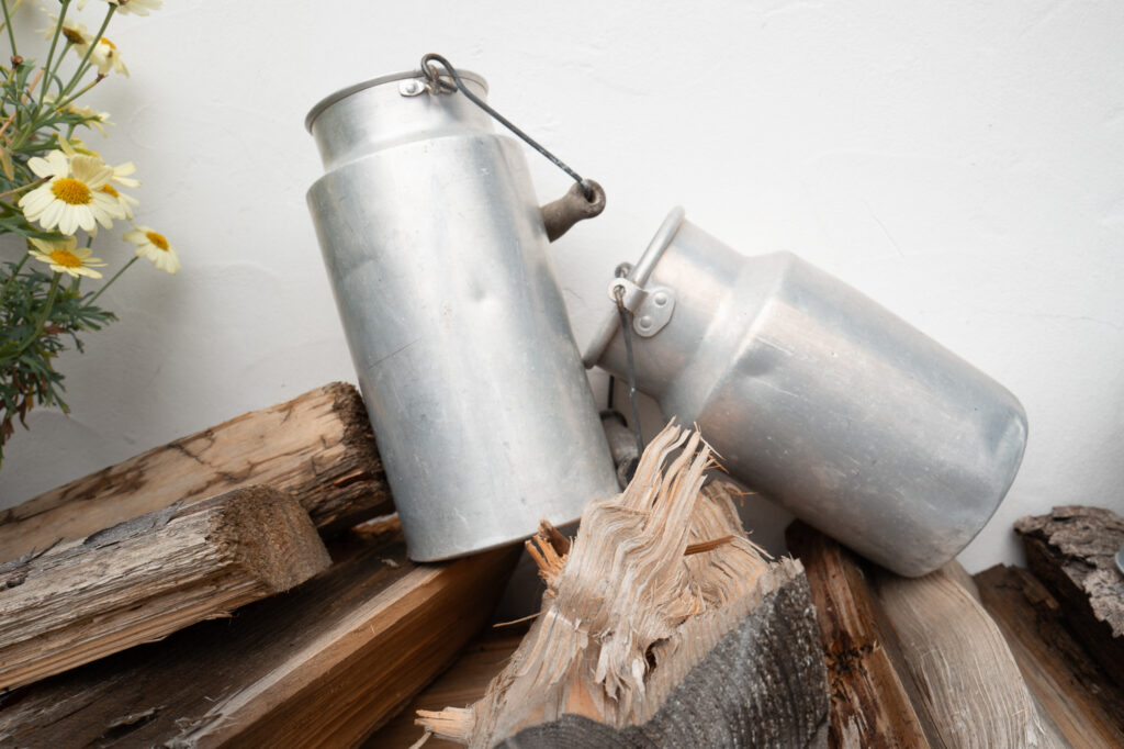 Milchkannen auf einem Holzstapel